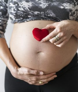 Pregnant woman holding a heart in front of her baby bump